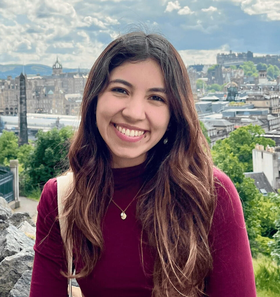 Picture of Mariana Rozo-Paz, the Youth4OurDataFuture Lead smiling while wearing a red sweater in front of a city landscape